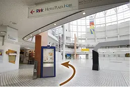 館内の通路。左上に「Hotel Plaza Kobe←」の案内サインがあり、その方向へオレンジ色の矢印が示されている。