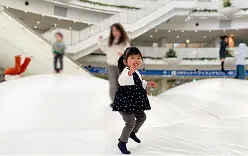 白いスロープが広がる屋内施設で楽しそうに走る子ども。