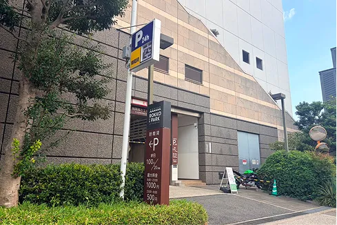 ビル1階にある地下駐車場の入口。周辺に「P」の看板が複数設置されている。