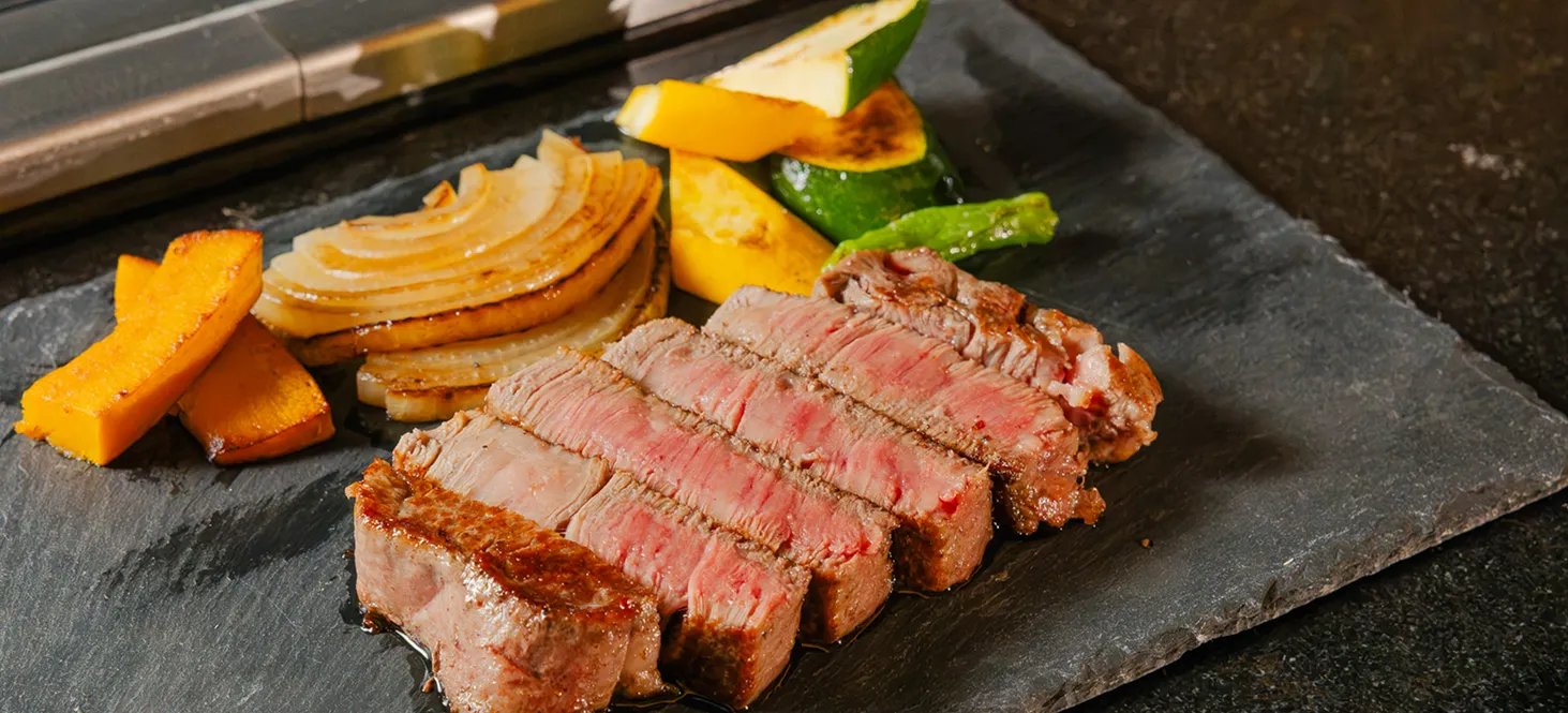 石盤に盛り付けられた、断面が美しい和牛ステーキと焼き野菜
