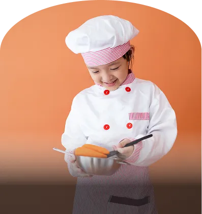 コック帽と衣装を身につけた子どもが、ボウルを持って調理体験をしている様子。