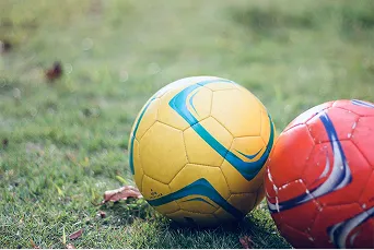 緑の人工芝グラウンドの上に置かれたサッカーボール