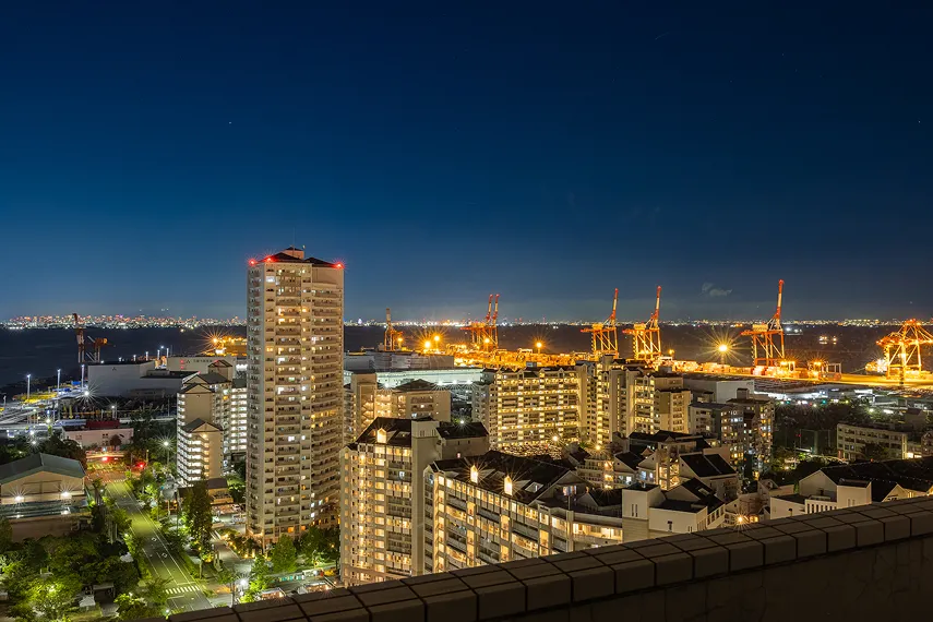 夜景に輝く高層ビルと港のクレーン
