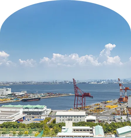 神戸の港を一望する眺め。赤いガントリークレーンや貨物船、青い海と空が広がる開放的な景色。