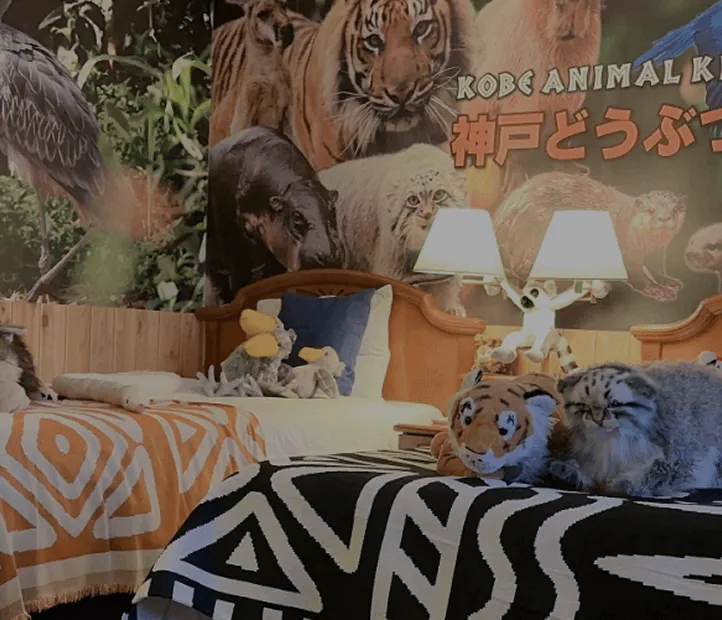 神戸どうぶつ王国の動物たちが描かれた壁一面のウォールアートが印象的なツインルーム。ベッドには動物のぬいぐるみが飾られている。