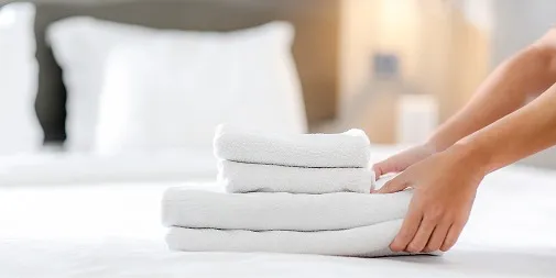 ベッドの上に、たたんだ白いタオルを重ねて置く手元