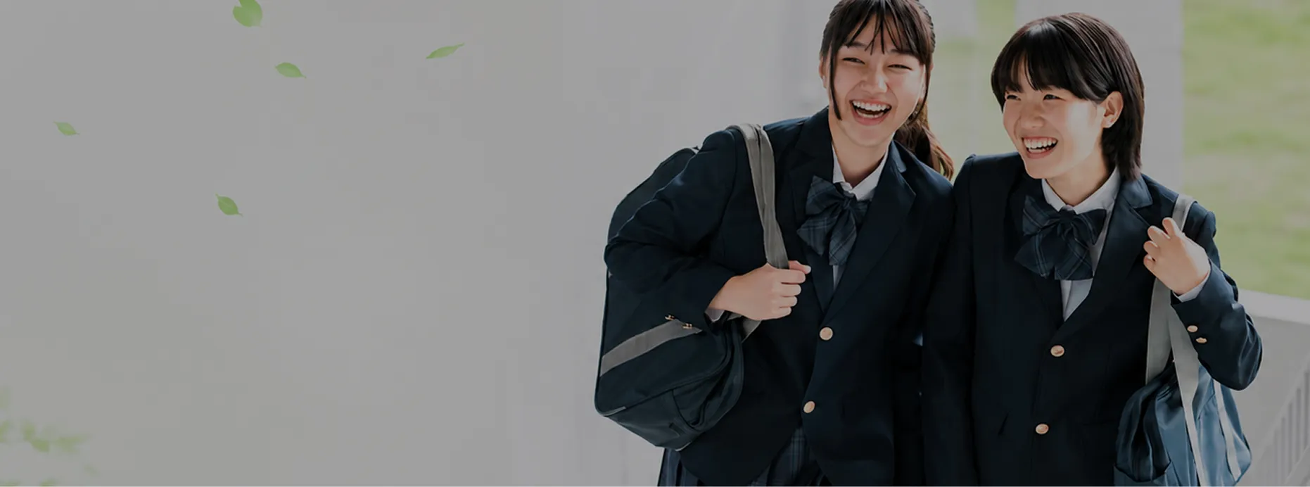 制服を着て笑顔で肩を組む2人の女子学生