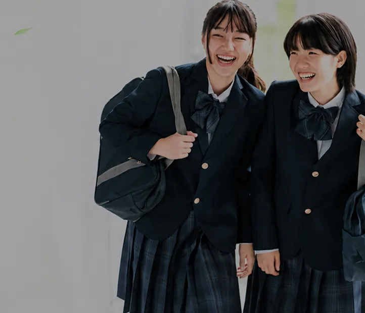 制服を着て笑顔で肩を組む2人の女子学生