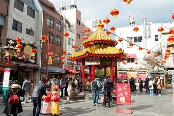 赤い提灯が連なる通りの中央に朱色と金色の東屋が建ち、多くの観光客でにぎわう南京町の広場