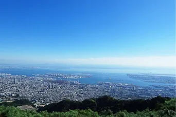 六甲山の山上から見下ろした、青空の下に広がる神戸の市街地と大阪湾の眺望