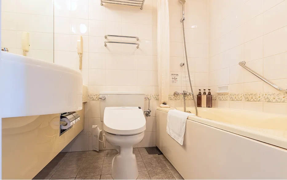 トイレとバスタブが一体となったユニットバス。洗面台や手すり、シャワーが備わっている。